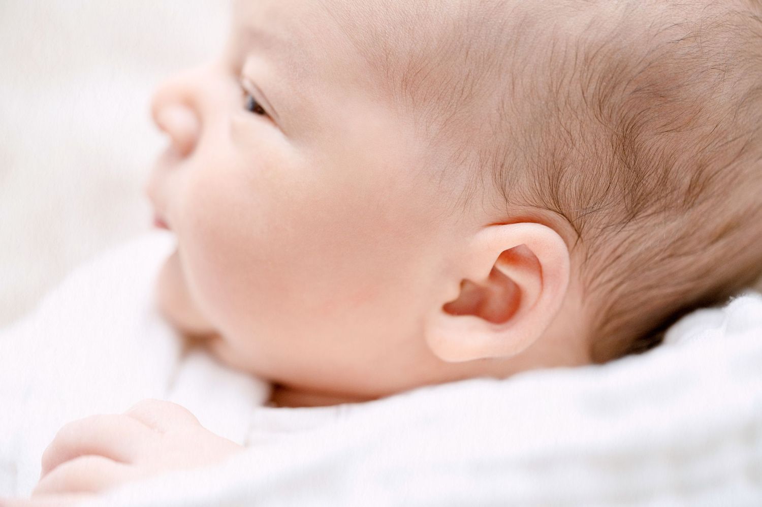 Soft profile view of sleeping newborn highlighting delicate features.