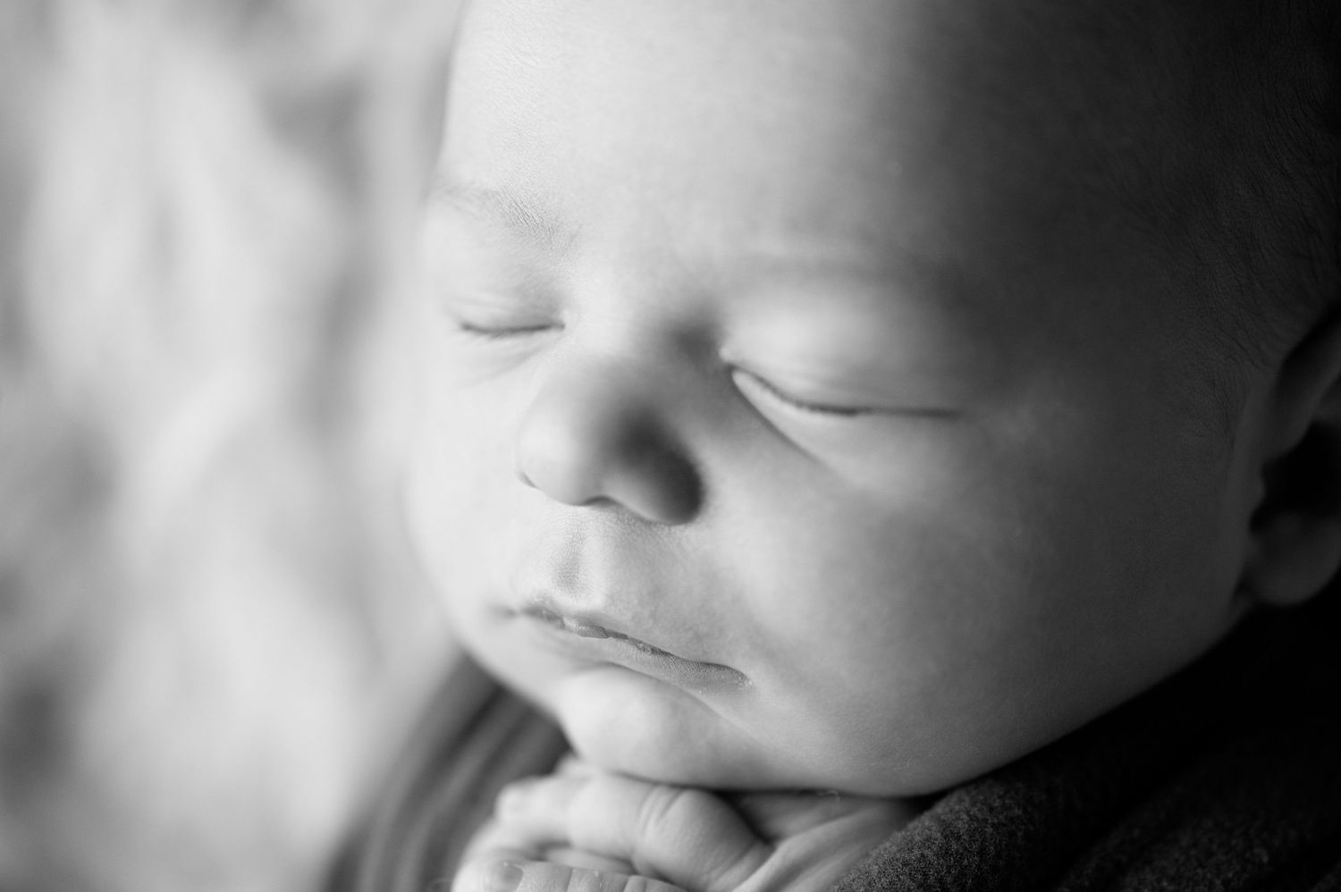 Black and white close-up portrait of a sleeping newborn.