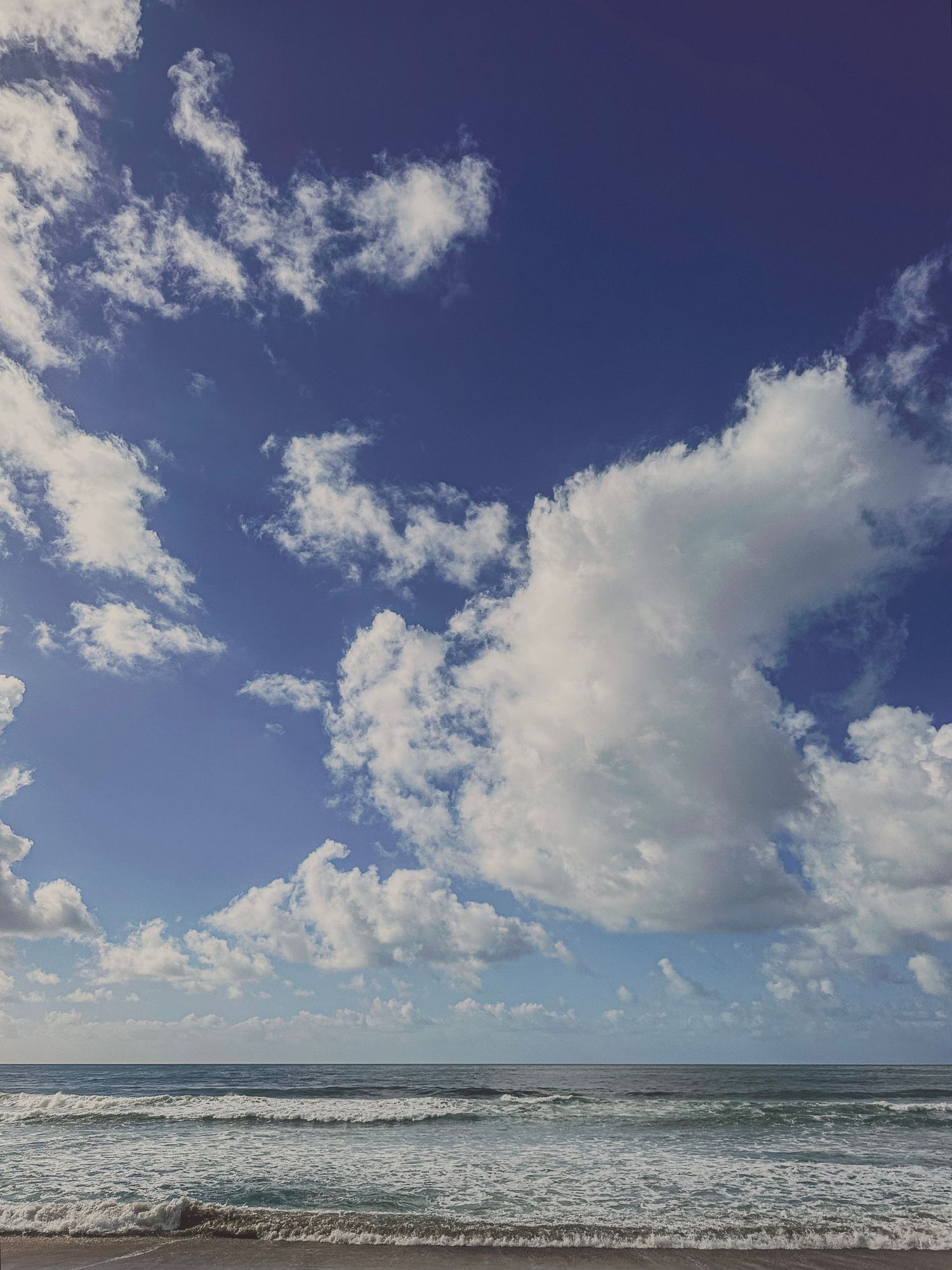 Beautiful seascape with white fluffy clouds over rolling ocean waves.