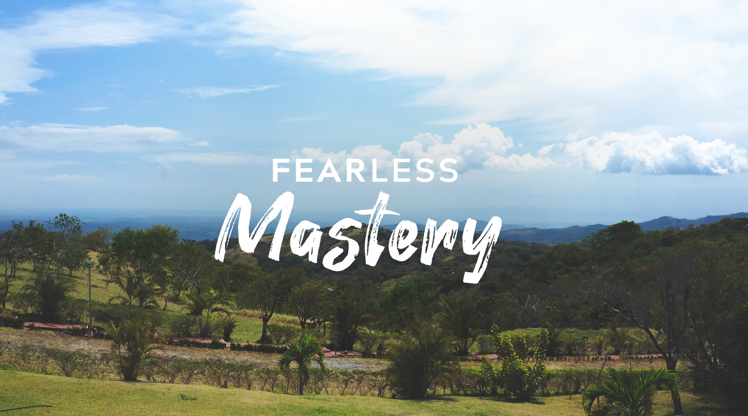 Scenic mountain landscape with text overlay reading 'Fearless Mastery' against blue sky and rolling hills.