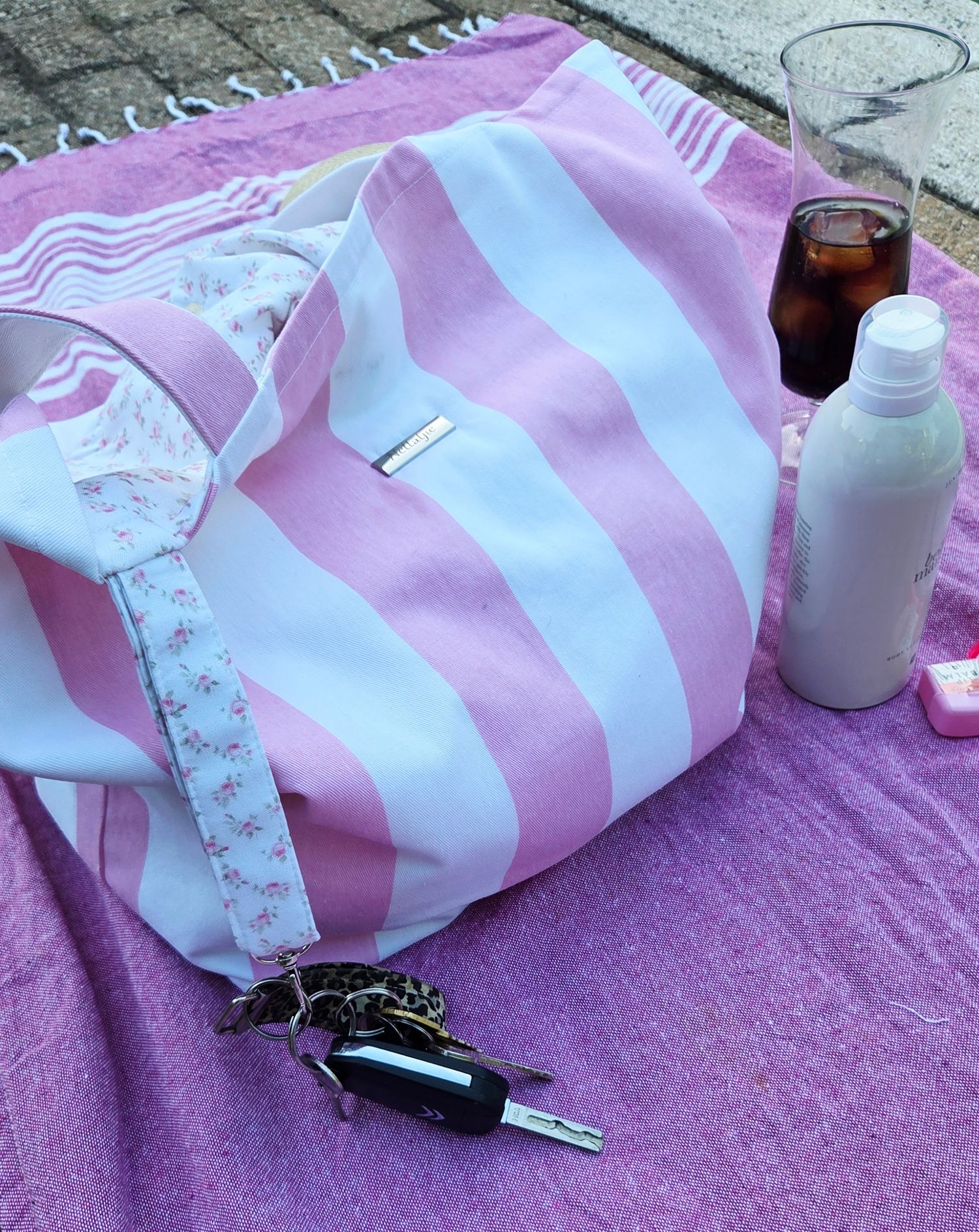 Close-up of a white hoodie with a pink floral pocket featuring cherry blossom embroidery, held by a hand with pink nails.