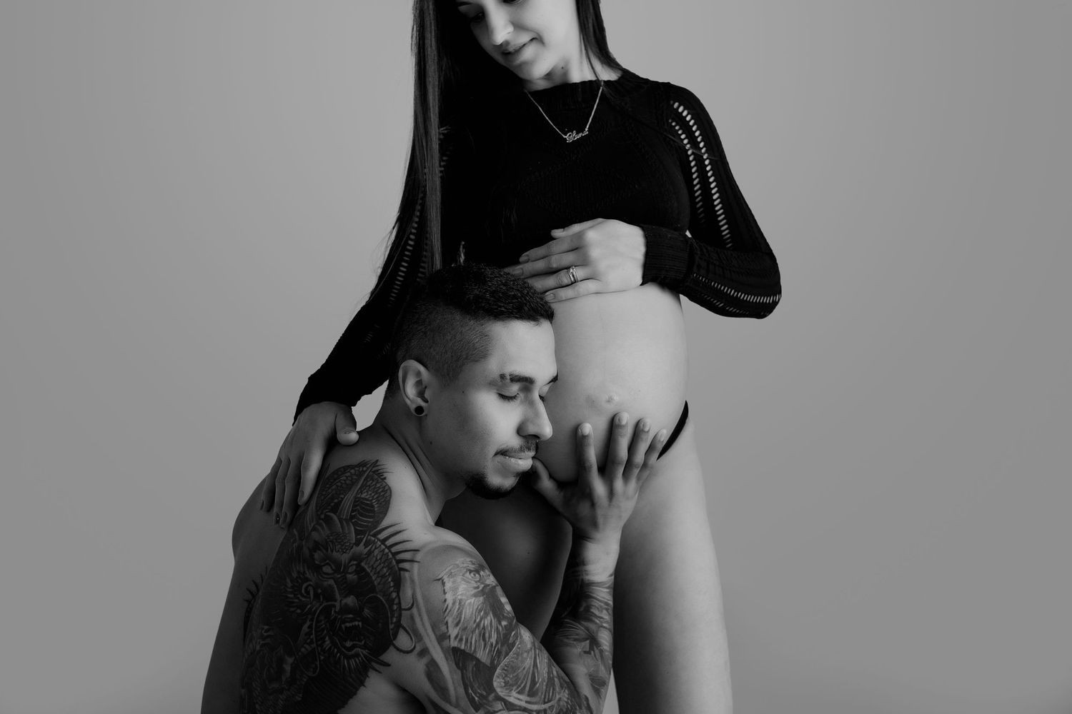 Artistic black and white maternity photo showing intimate couple moment.