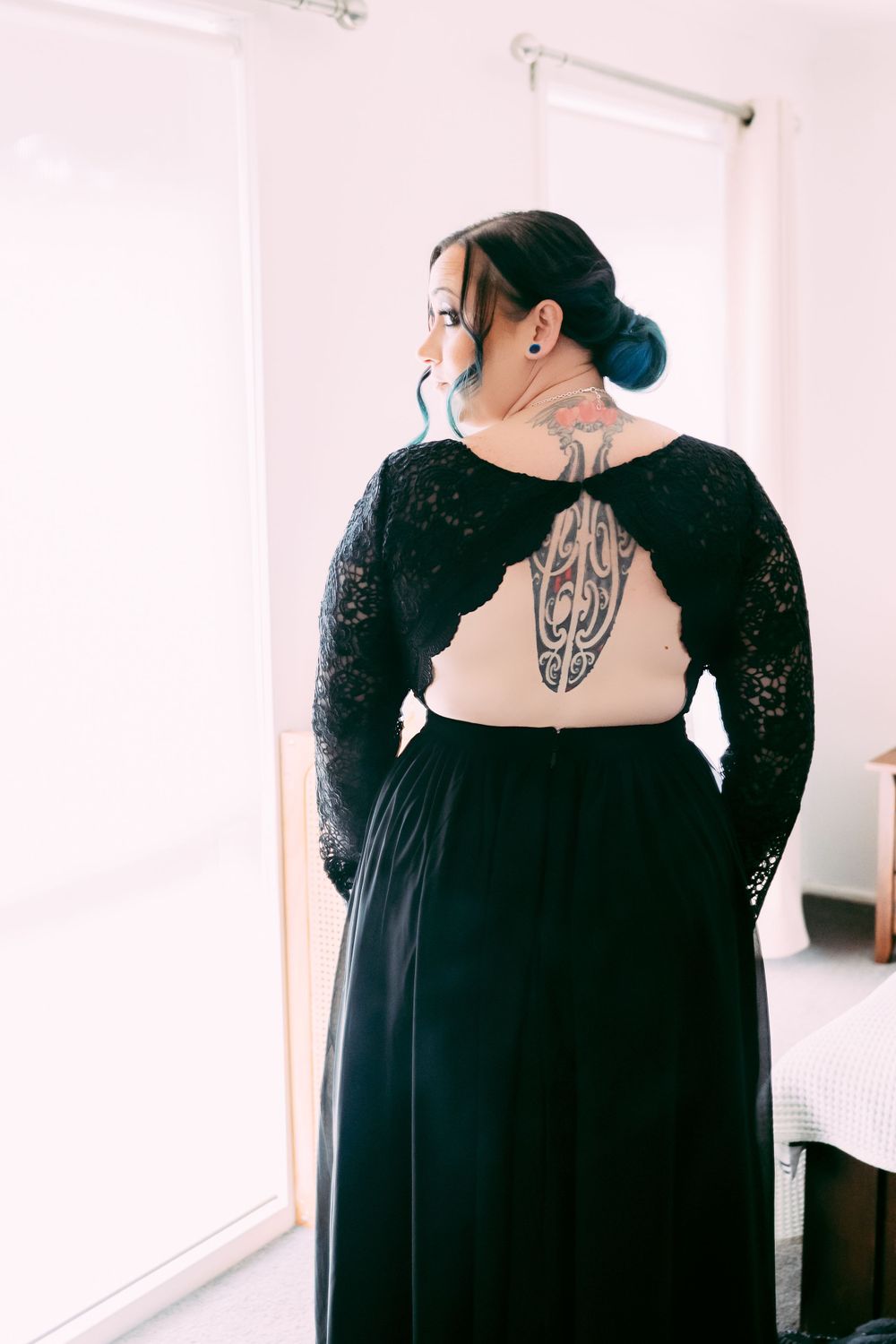 Back view of black lace dress revealing intricate back tattoo design.