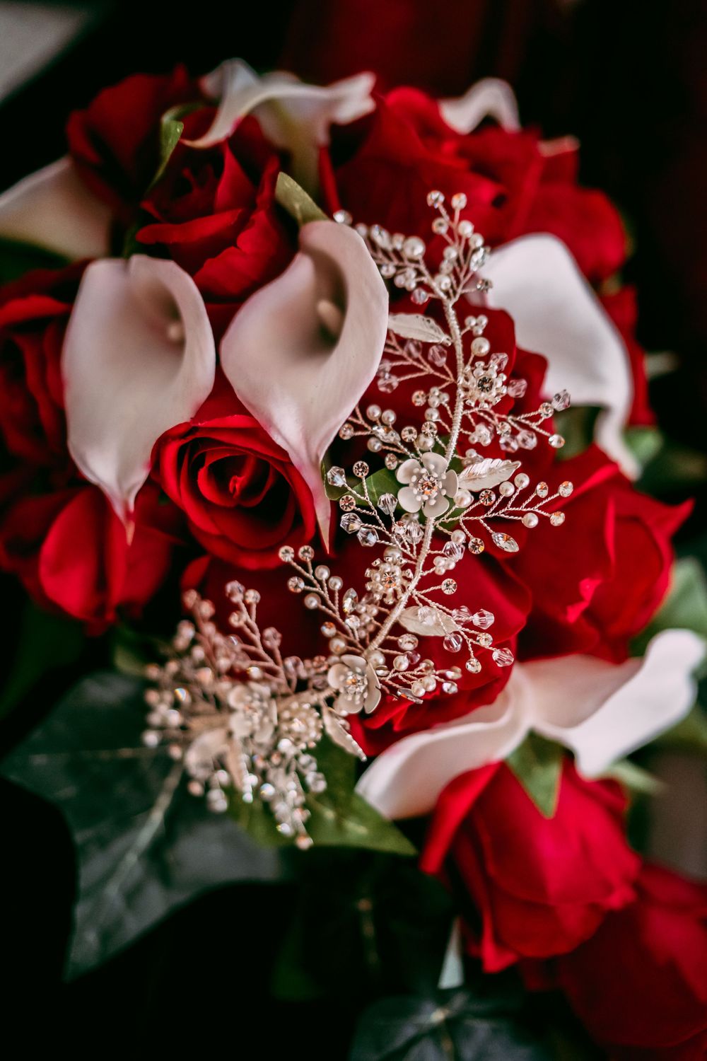 Elegant wedding bouquet with red roses, white calla lilies and silver baby's breath.