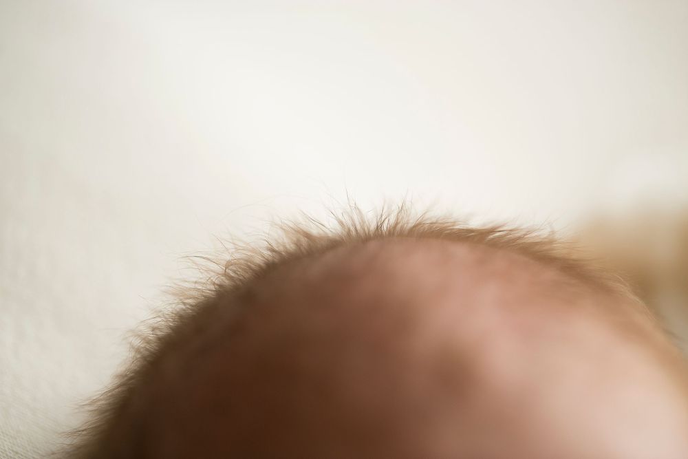 Newborn baby boy closeup of red fuzzy hair.