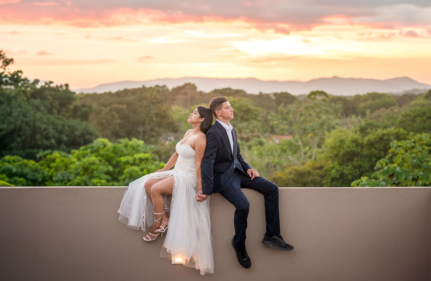 Couple sitting back to back, holding hands, with the lush Costa Rican forest in the background Botanika Osa Peninsula