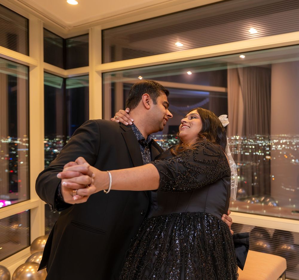 Couple dancing together in a high-rise room with city lights glowing through large windows at night.