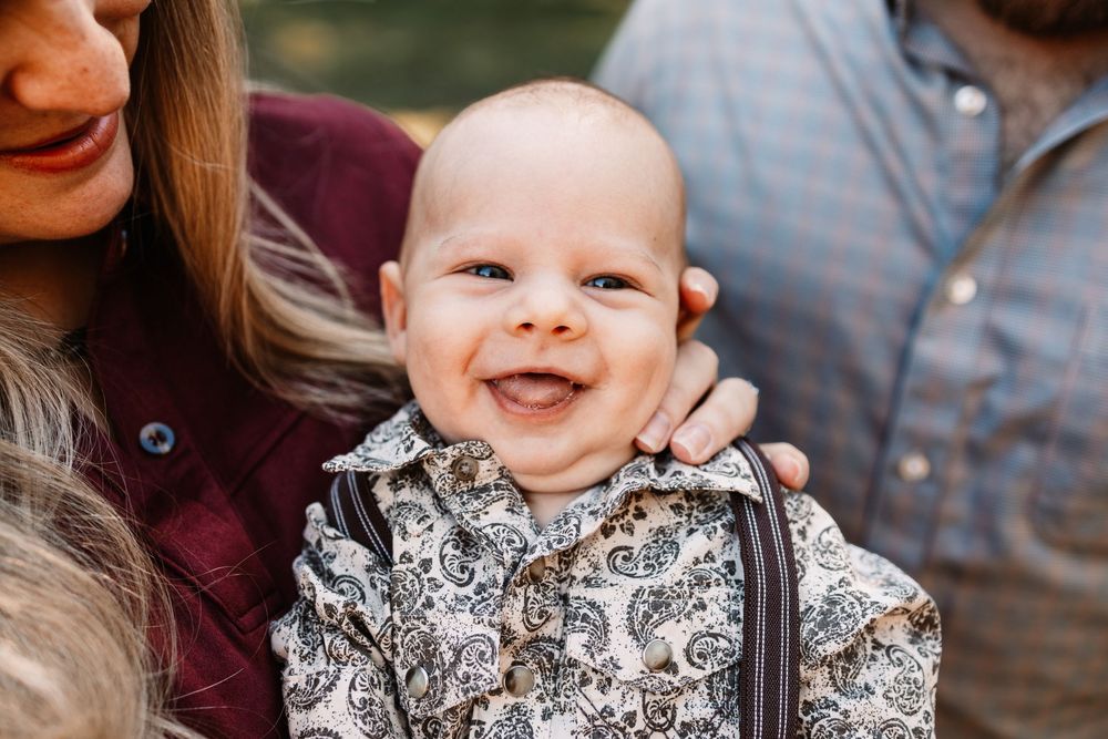 Smiling baby in a paisley print outfit with suspenders during a family photo session in Knoxville, TN.