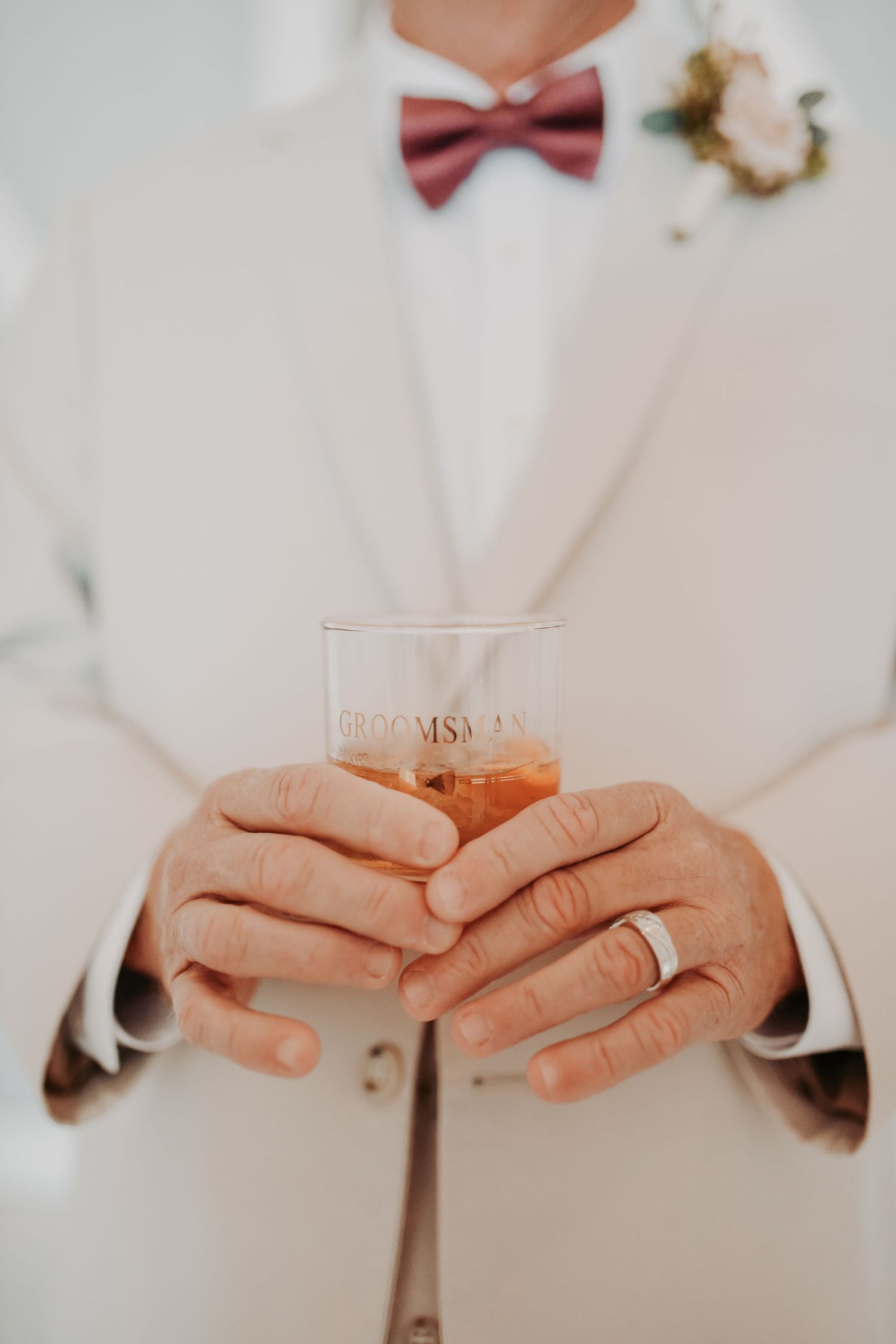 Groom wearing an oatmeal linen suit with a mauve bow tie for a romantic fall wedding