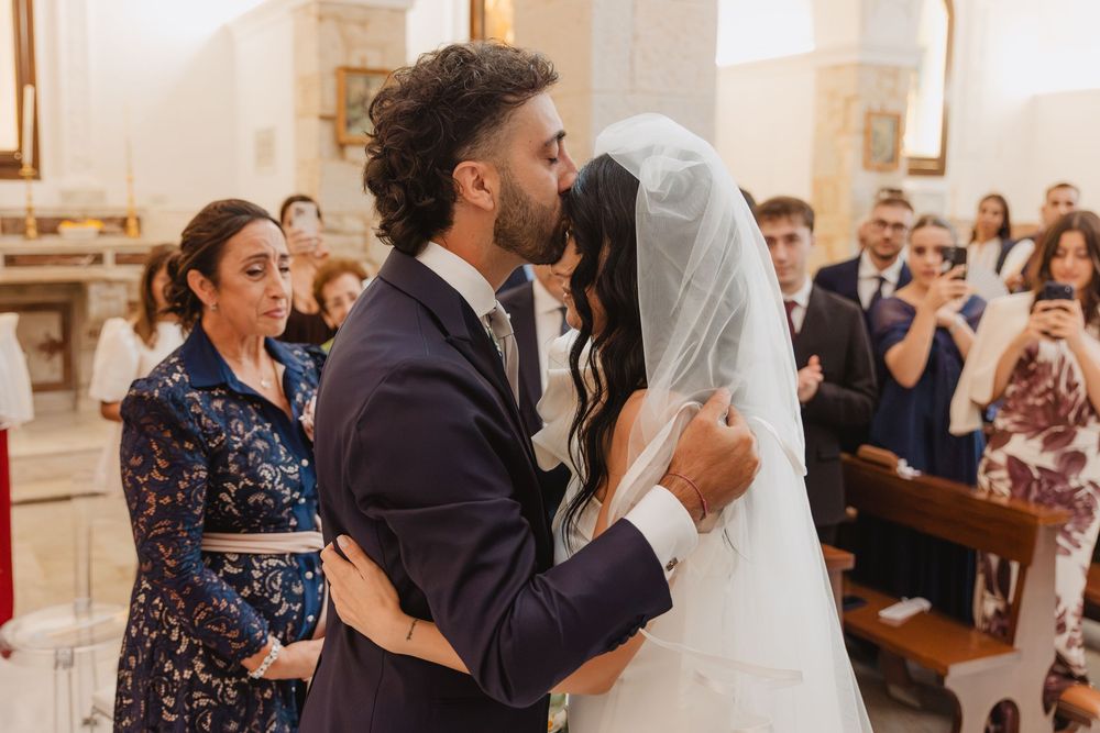 Lorenzo e Laura si salutano con un bacio davanti agli invitati in chiesa.