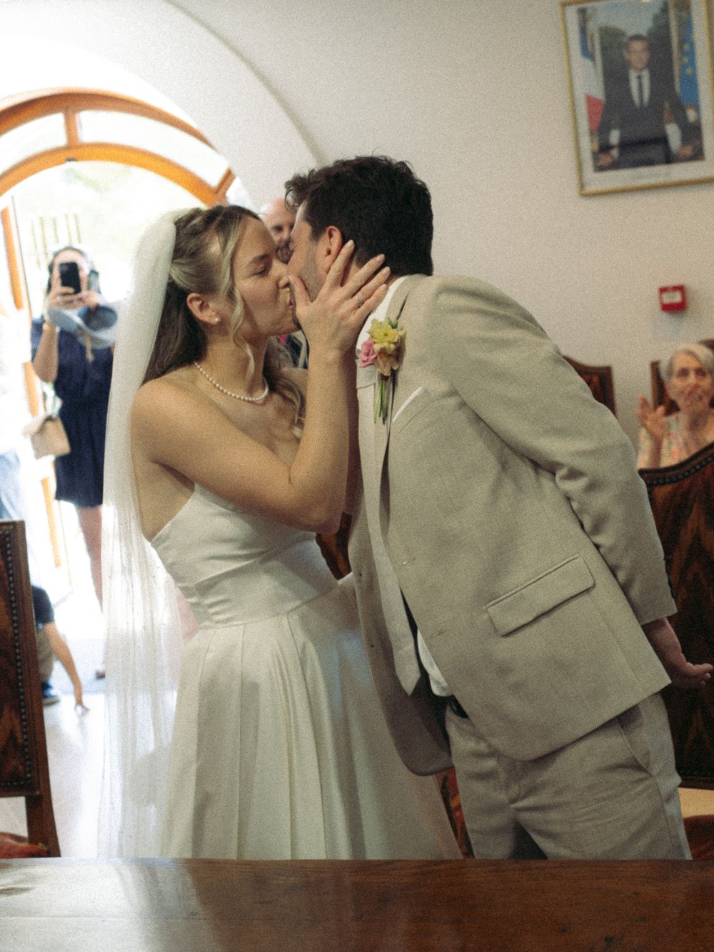 Bride and groom sharing their first kiss at a wedding ceremony indoors.
