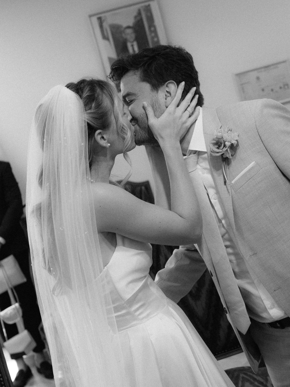 Black and white photo of a bride and groom sharing their first kiss at a wedding ceremony.