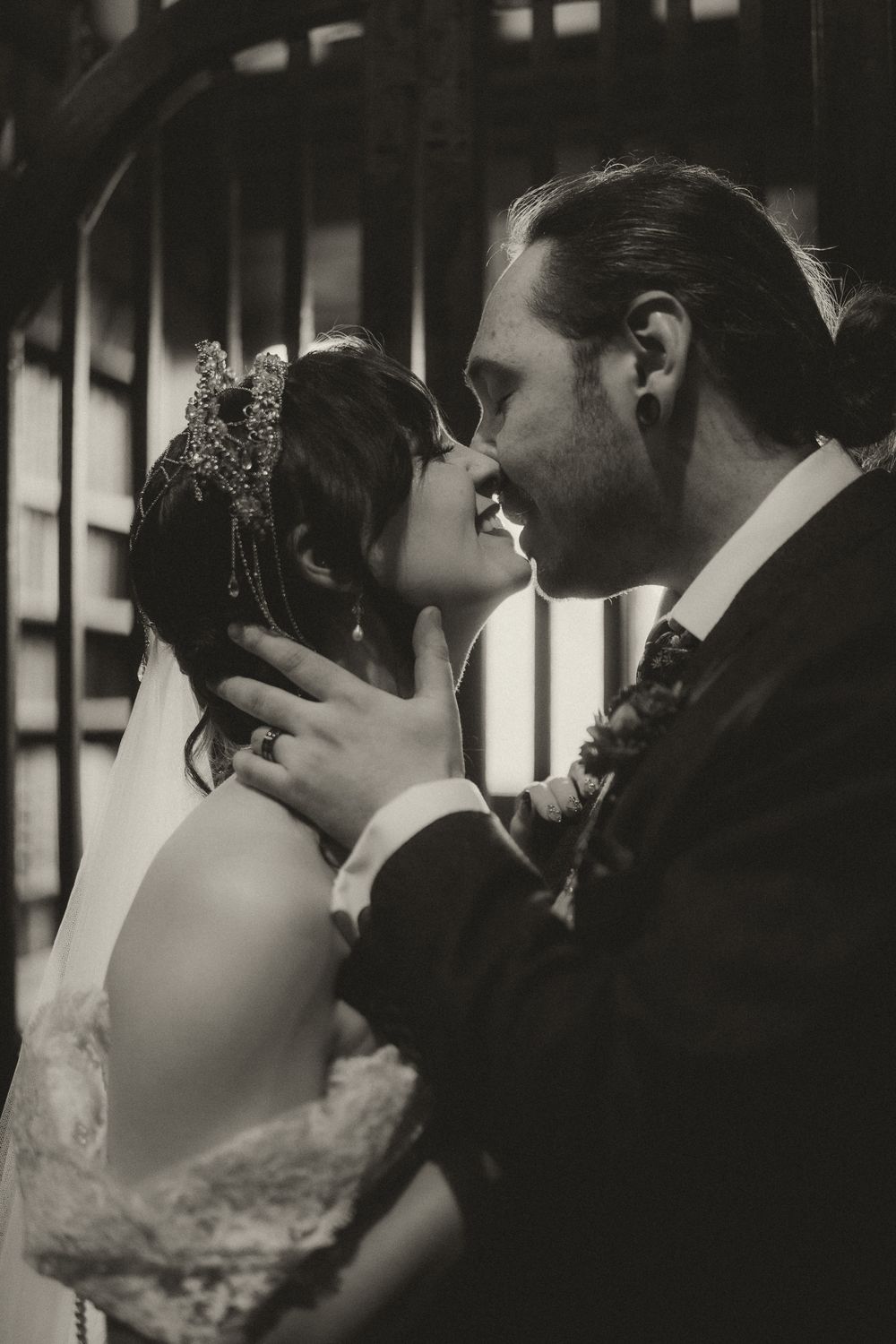Black and white photo of a bride and groom sharing a romantic almost-kiss, bride wearing lace dress and floral crown.