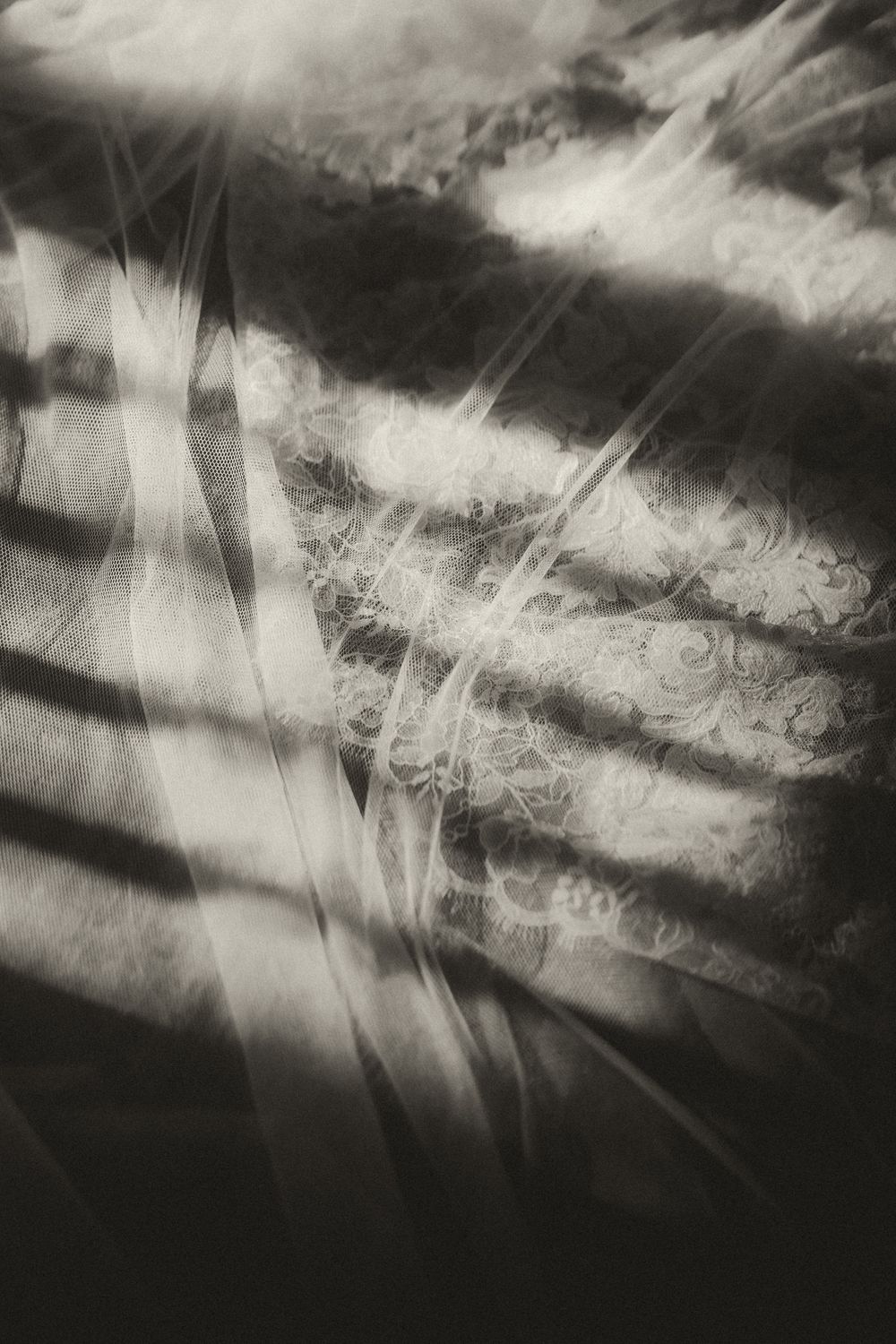 Abstract black and white photo of light and shadows on textured lace fabric with dramatic diagonal lines.
