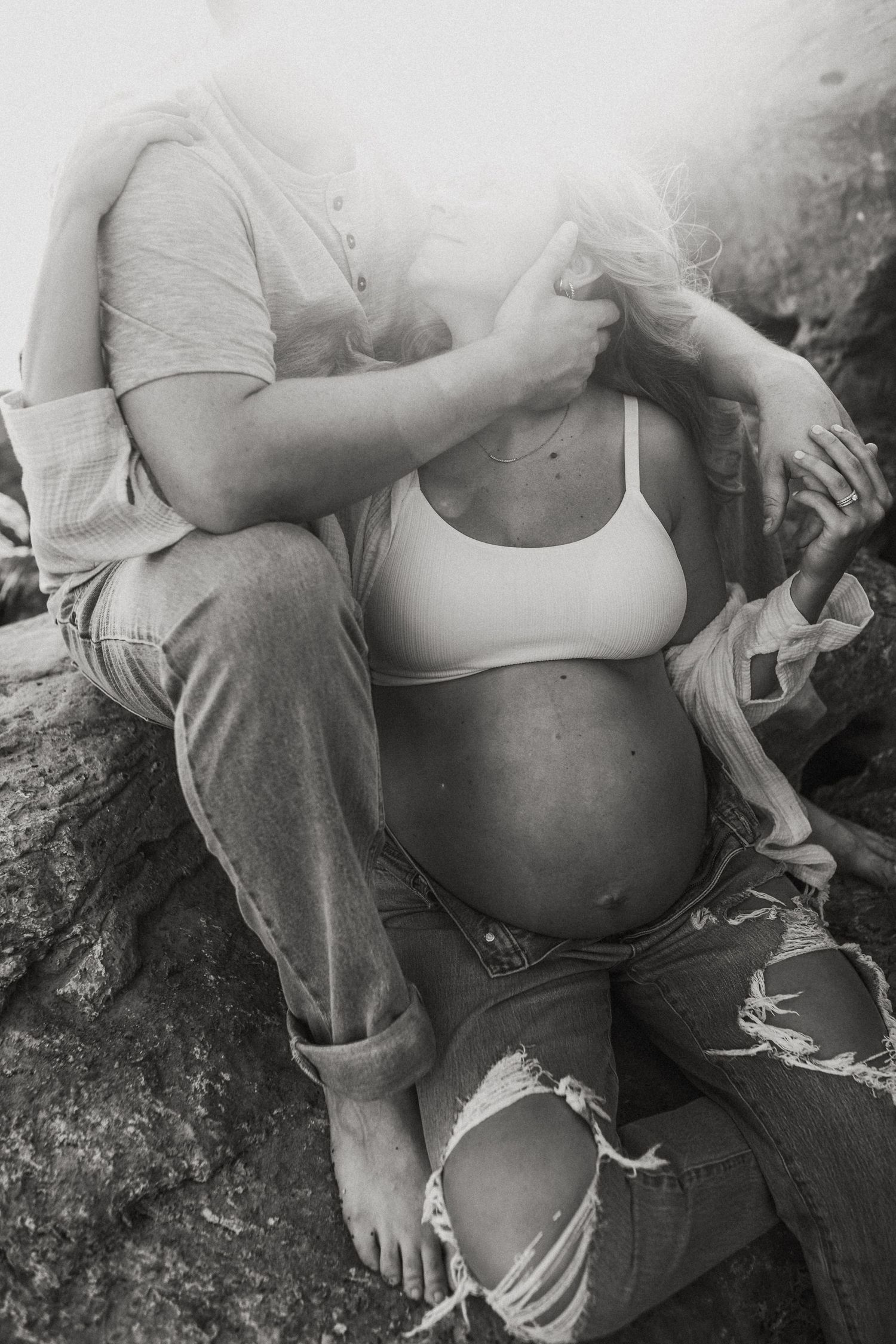 Candid maternity photo of expecting parents laughing together beside Lake Grapevine