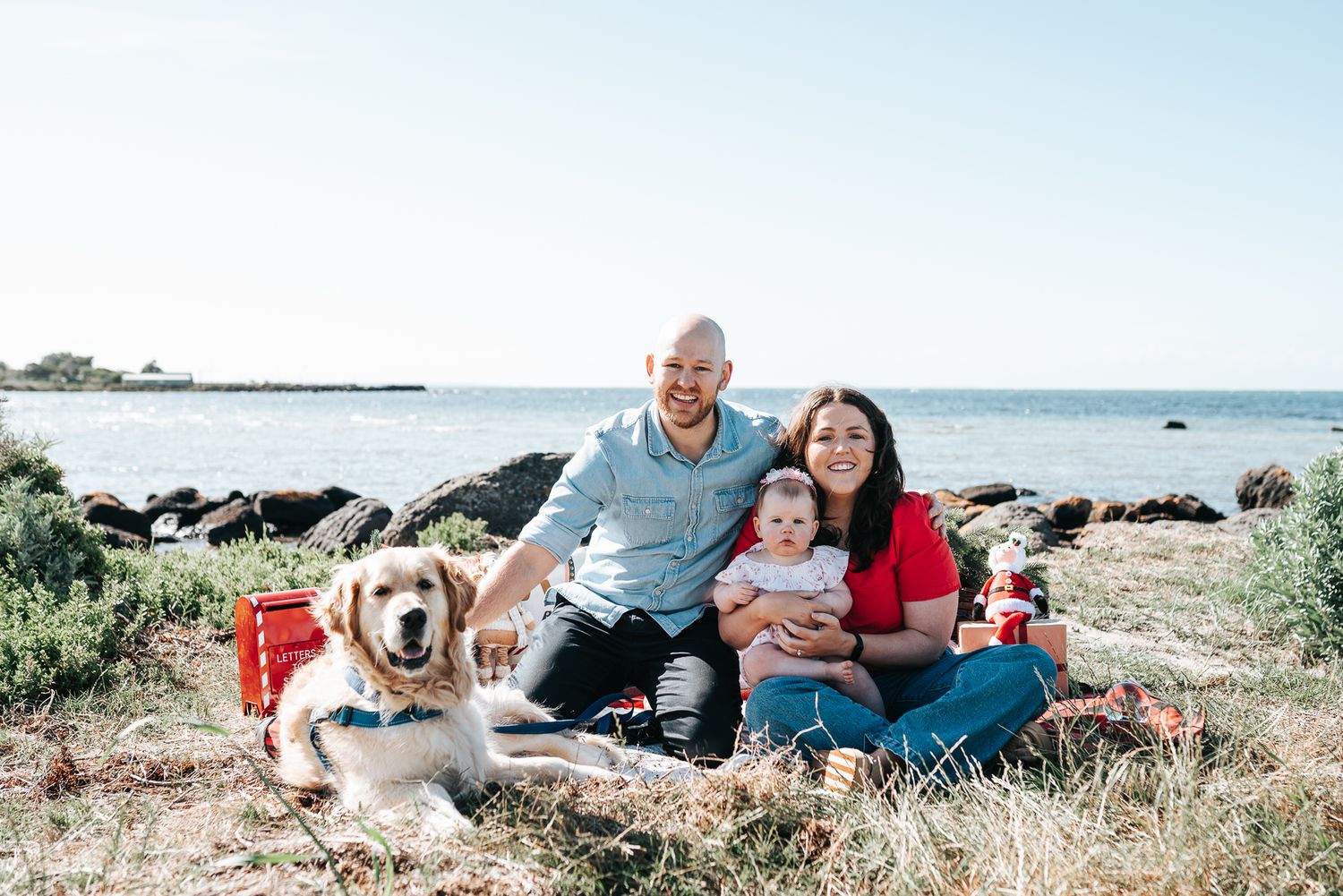 A family of three with their dog posing for a family Christmas portrait at Jawbone Marine Sanctuary in Melbourne.