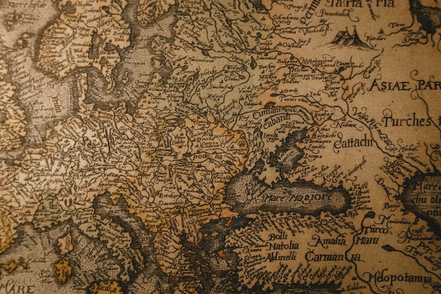 Antique vintage world map with aged brown tones showing Europe and Asia regions with Latin text.