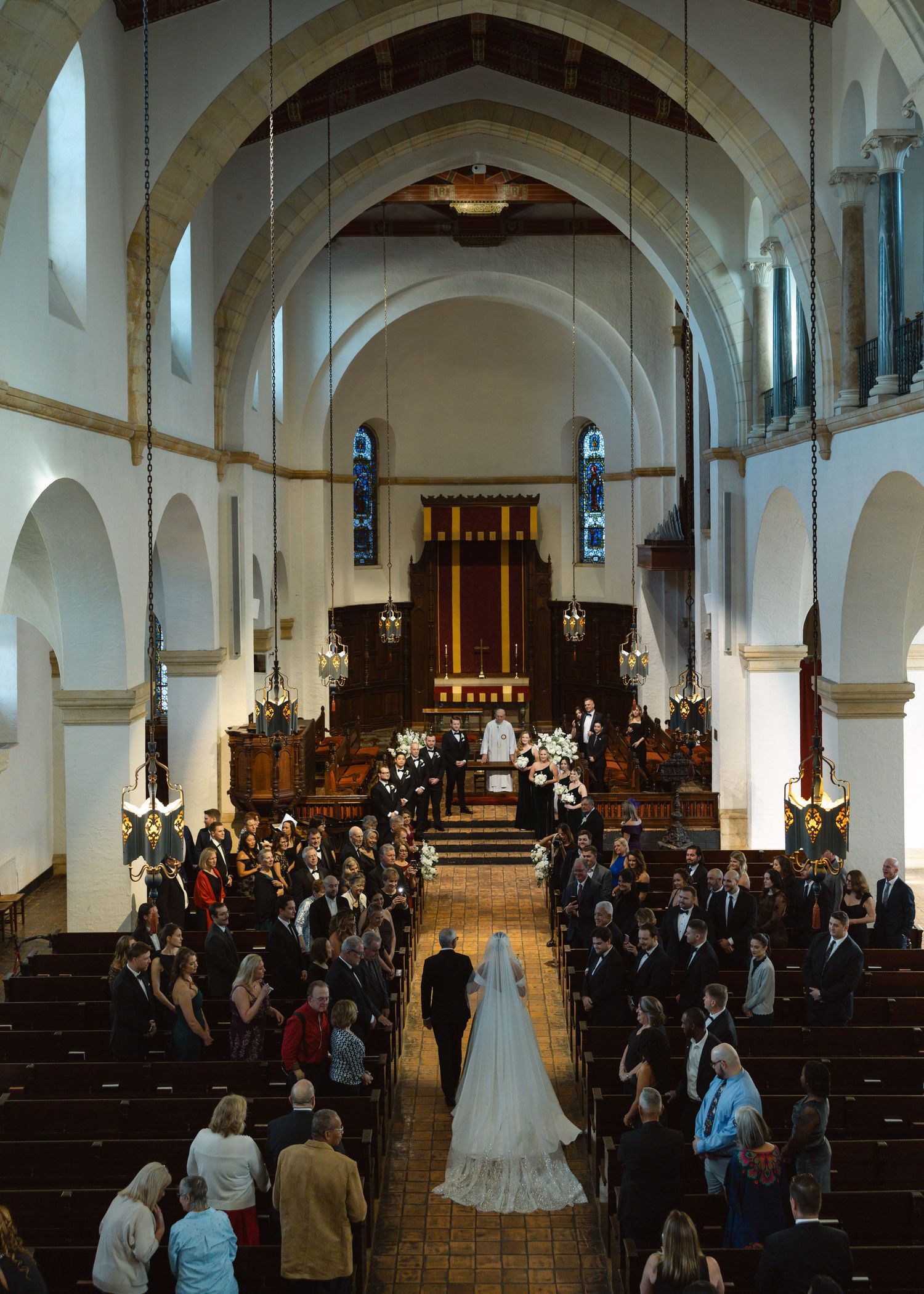 Bride walking down the aisle in a church wedding ceremony with guests seated in wooden pews.