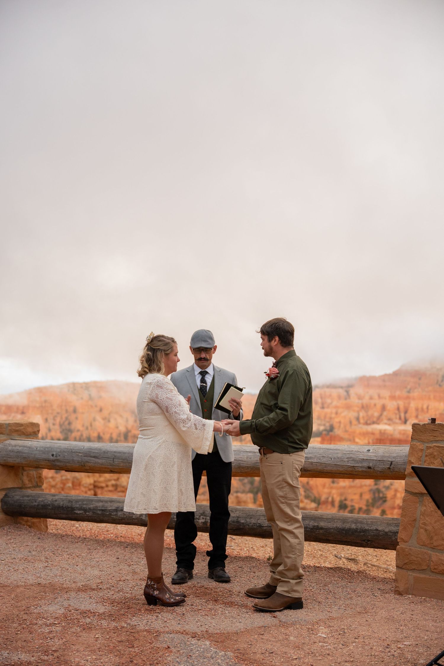 Couple exchanges vows with officiant at Bryce Canyon overlook during intimate outdoor wedding ceremony.
