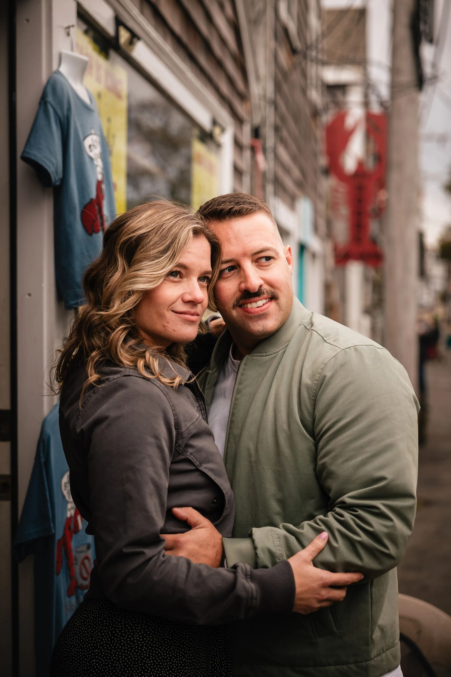 Couple embracing and smiling at the camera in an urban alley.  Engagement at Rockport Harbor, Rockport, MA