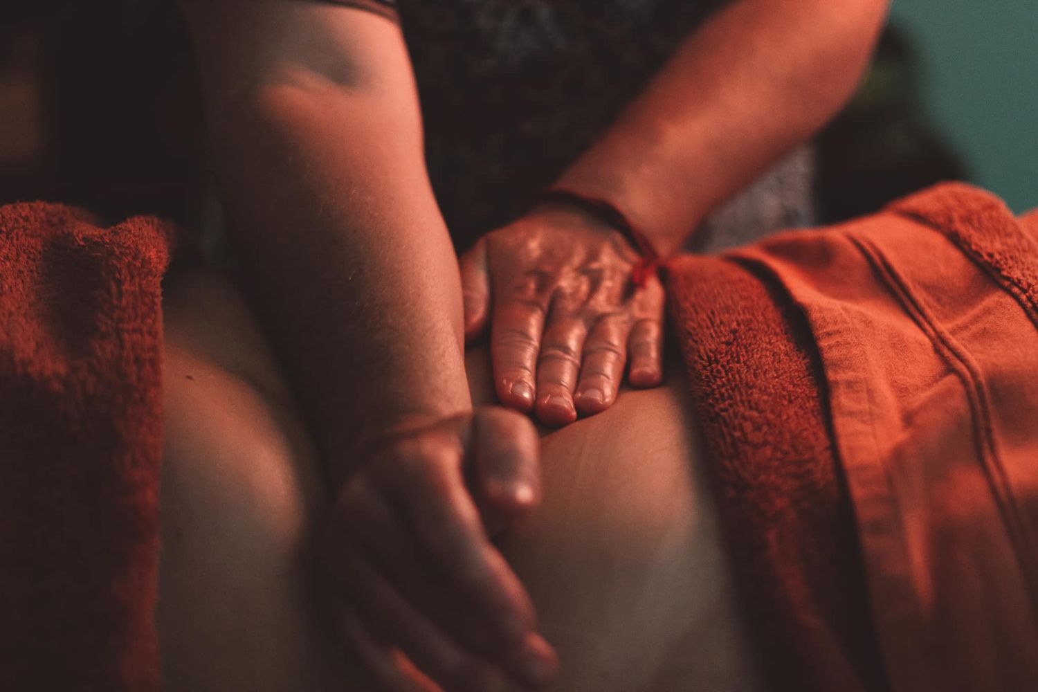 Close-up shot of hands touching against warm red lighting.