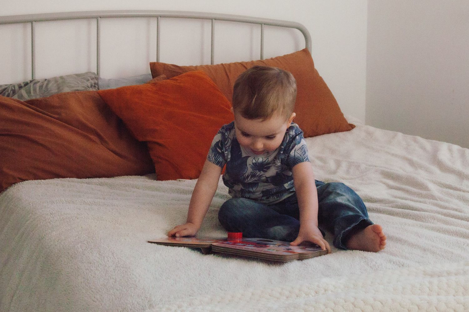 toddler reading his favourite book on the bed, photographed by Maria Photography, a family photographer in Gosport.
