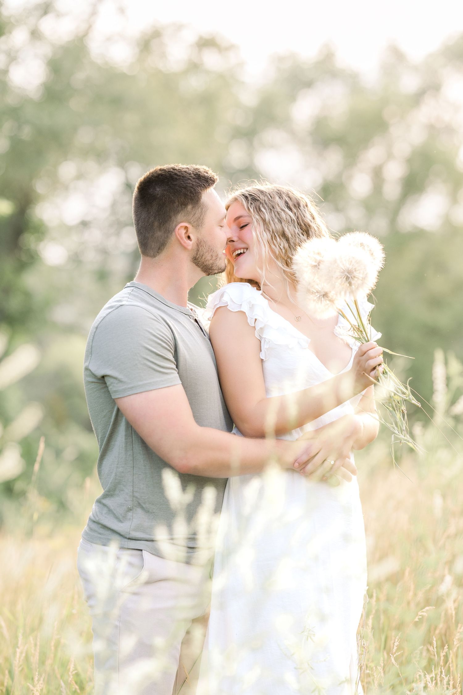 A romantic couple embracing in a sunlit field with golden grasses.