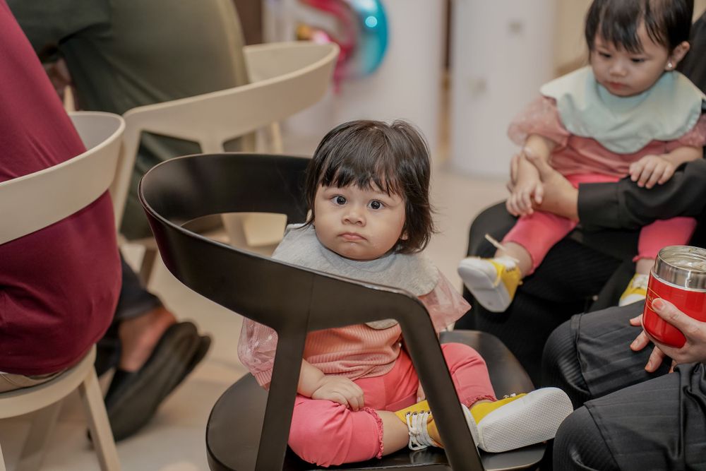 A young guest sitting in a chair during a festive indoor celebration.