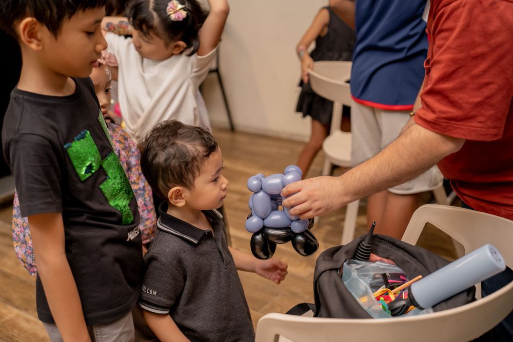 Children watching as toys are being distributed from container at party.