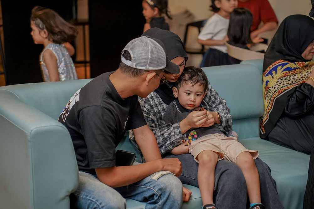 Adult and child sitting together on a blue couch during a casual indoor gathering.