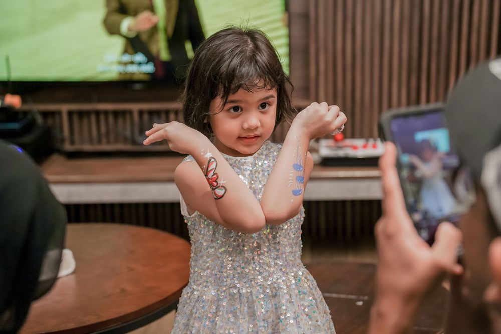 A young partygoer showing off temporary art decorations on their arms.