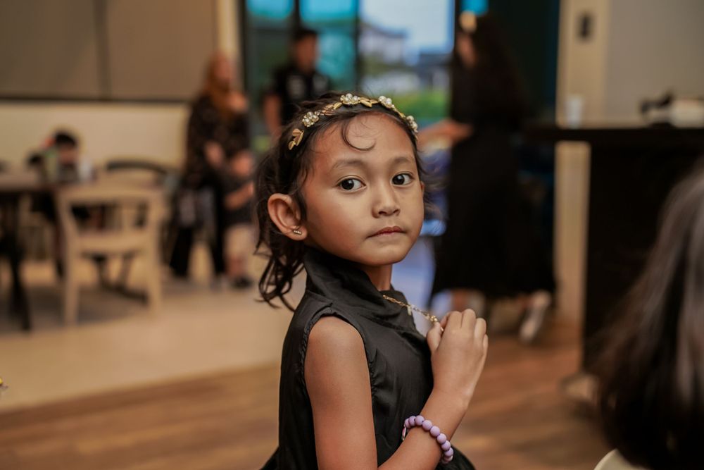 A young guest in formal attire at an indoor celebration event.