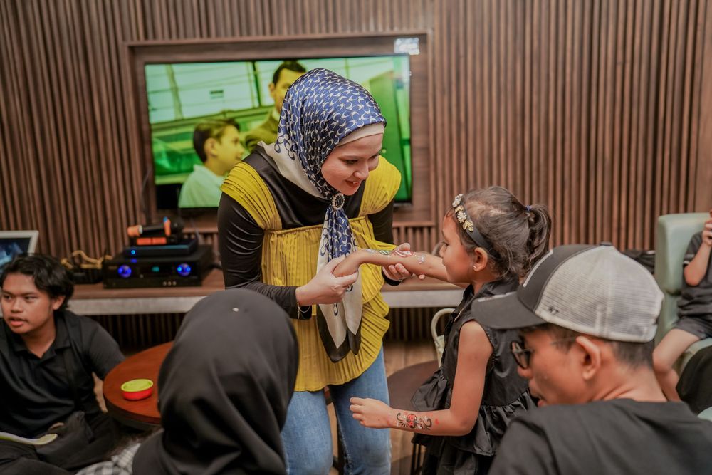Group gathered around TV with person in yellow vest interacting with others.