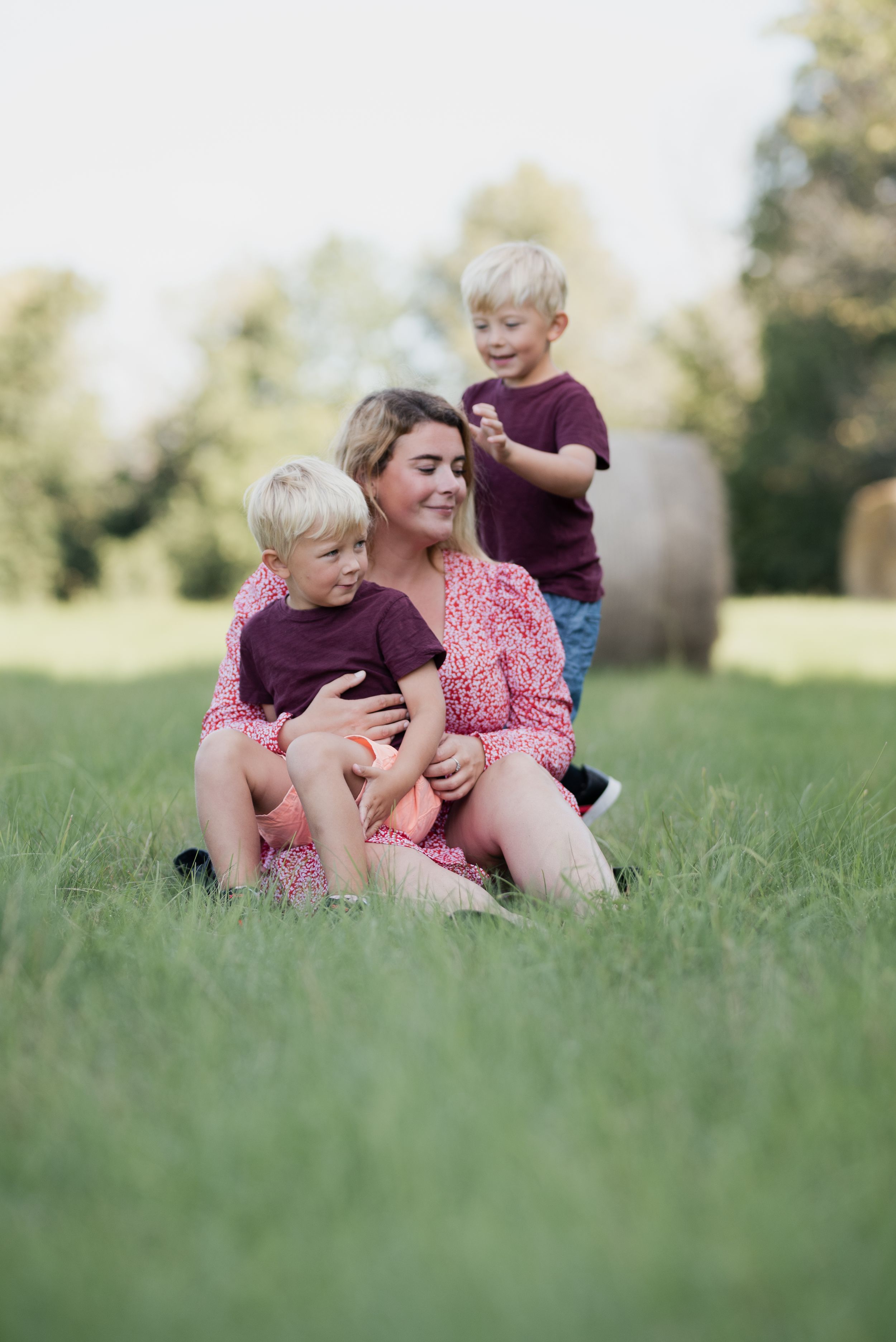 Family shares playful moment together sitting in sunny green field.