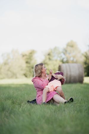 Candid moment of joy shared between family members in sunlit meadow.