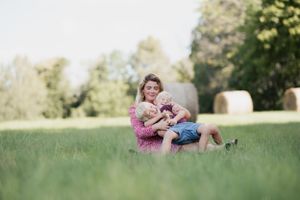 Intimate family moment captured in a serene field setting during golden hour.