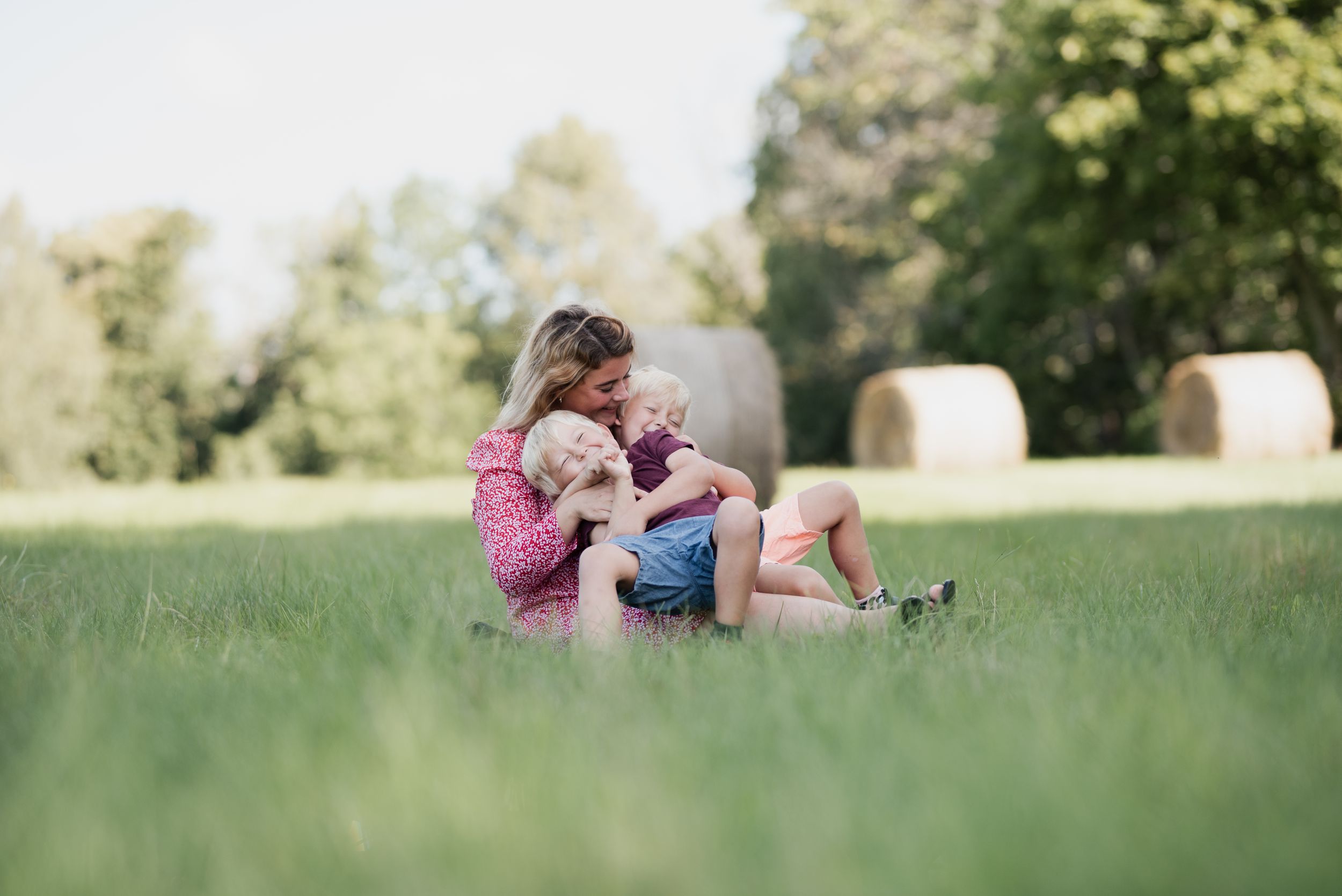 Peaceful moment shared on grass with hay bales visible in the distance.