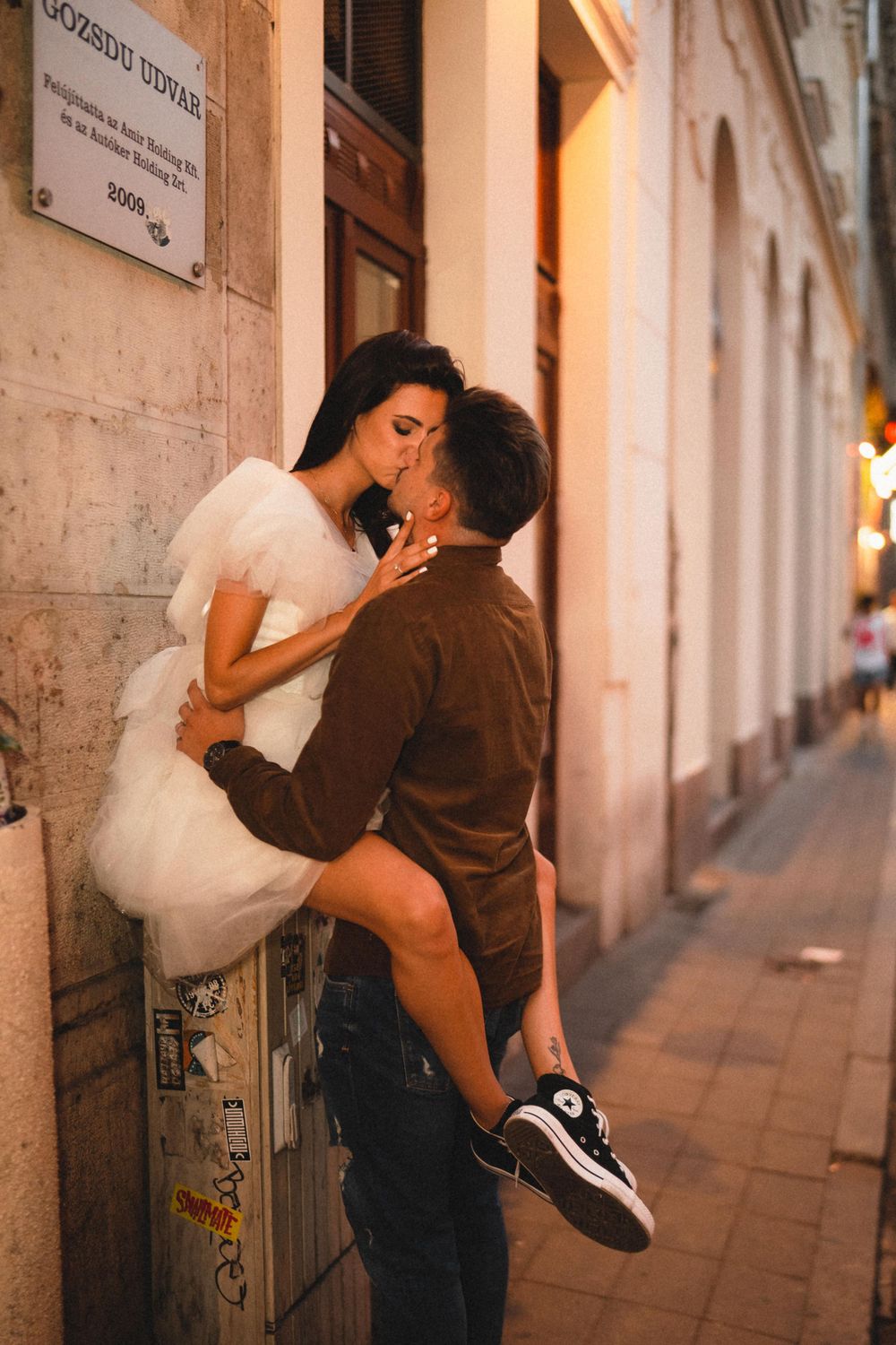 Romantic embrace against urban wall with warm evening lighting.