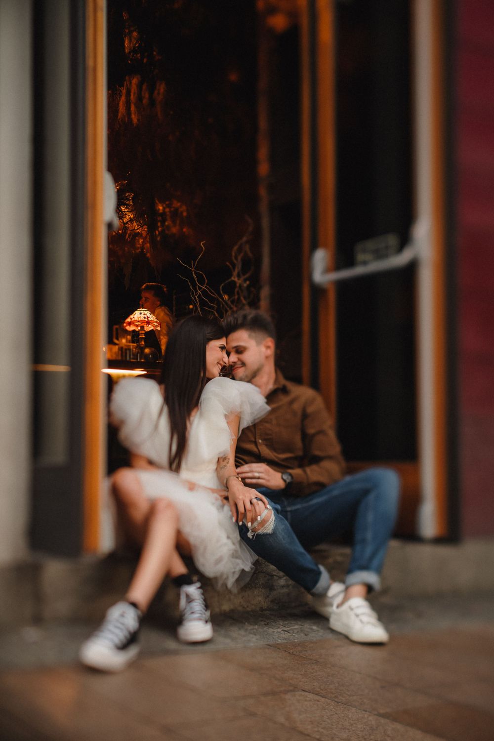 Intimate couple moment captured in doorway with atmospheric orange lighting.