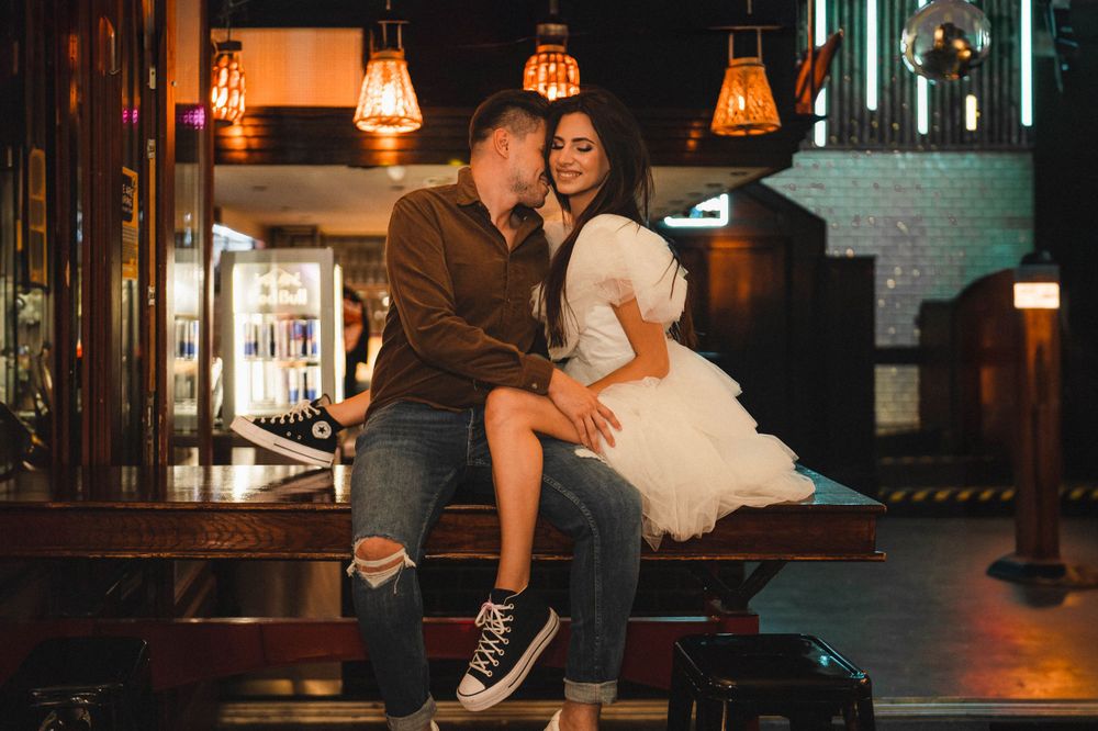 A couple sharing an intimate moment on a bench under warm bar lighting.