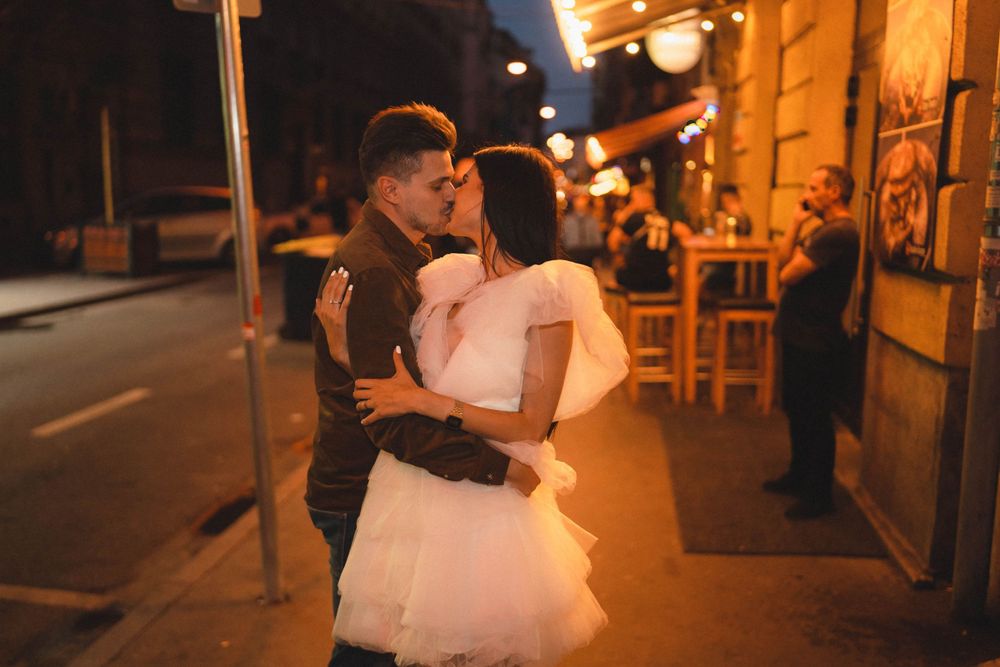 Couple dancing on nighttime city street with warm ambient lighting.