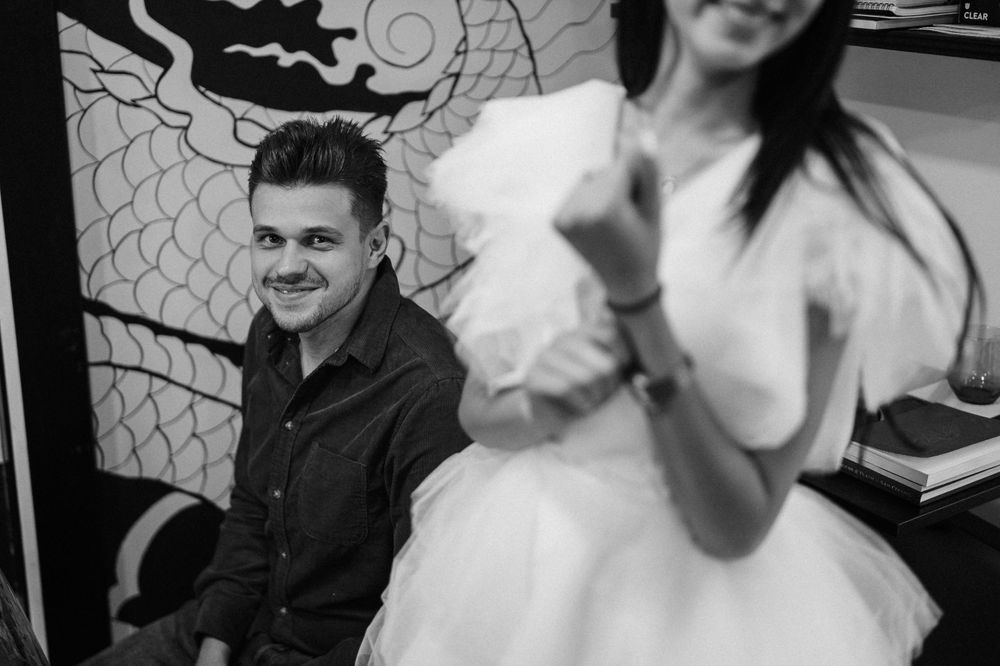 Black and white photo of people sitting together against decorative wall art.