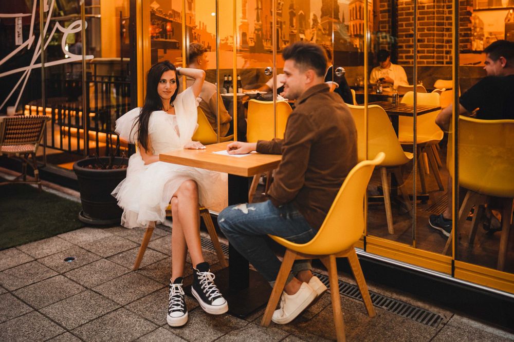 Romantic date at outdoor cafe with yellow chairs and warm evening lighting.