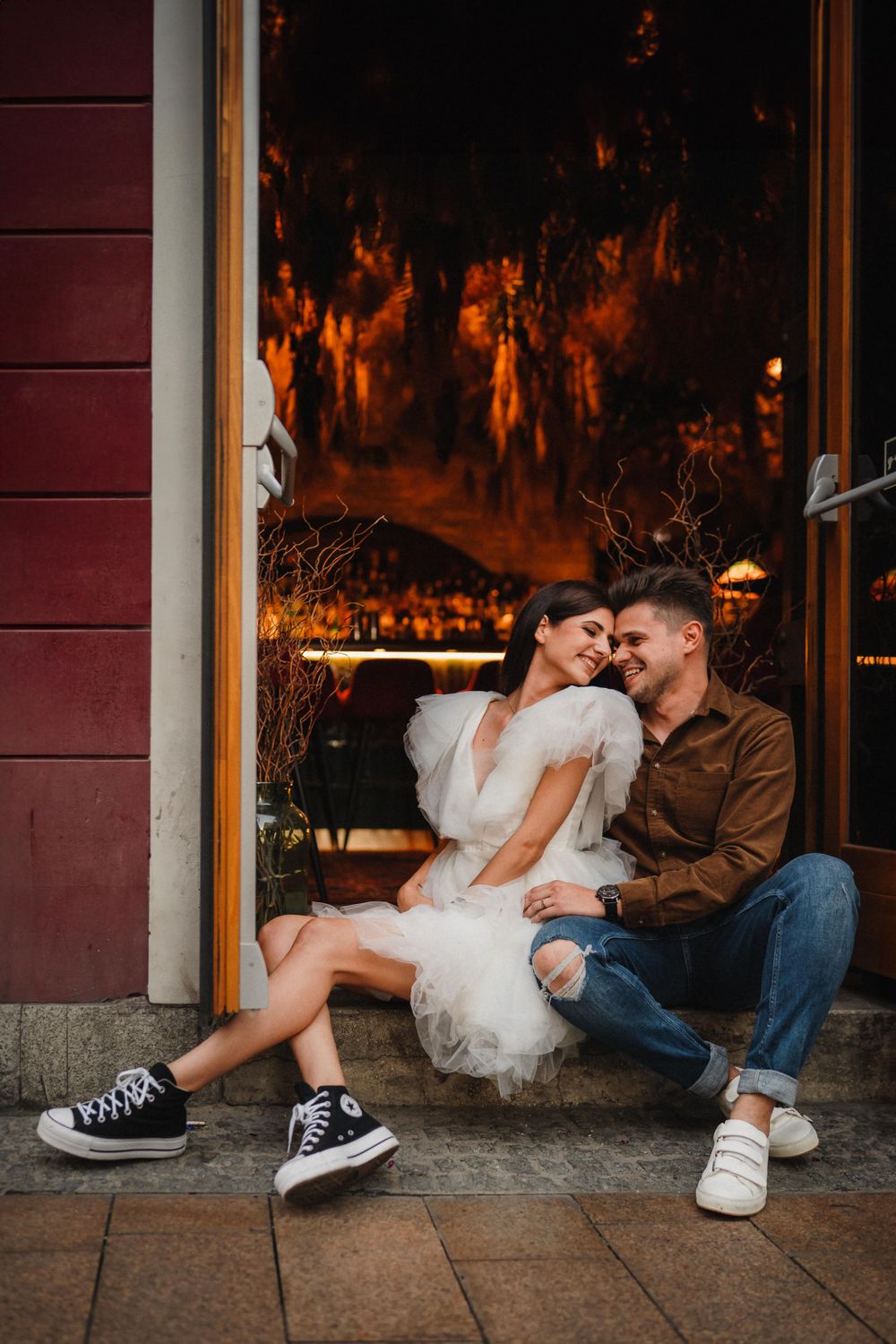 Romantic couple sharing tender moment in doorway with orange-lit backdrop.