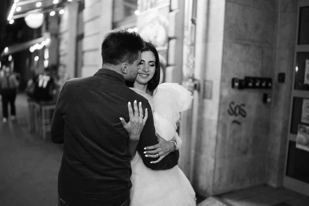 Black and white nighttime street scene with couple embracing.