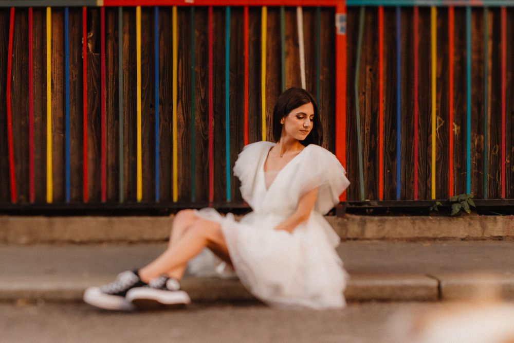 Fashion portrait with white dress against colorful striped wall background.