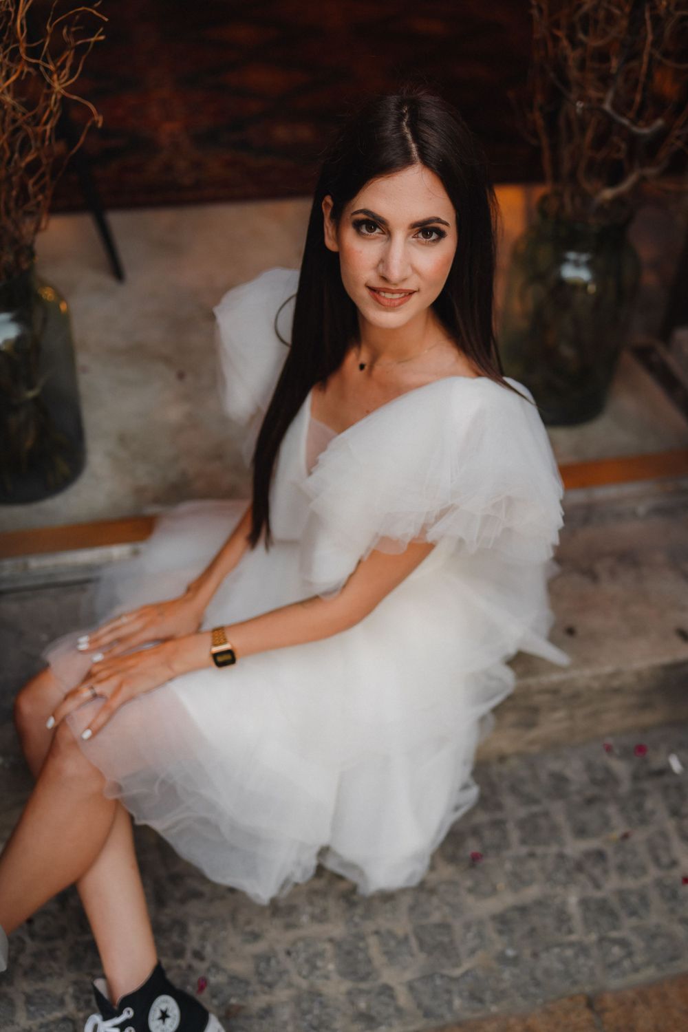 A white tulle dress creates a romantic mood while sitting on stone steps in warm lighting.