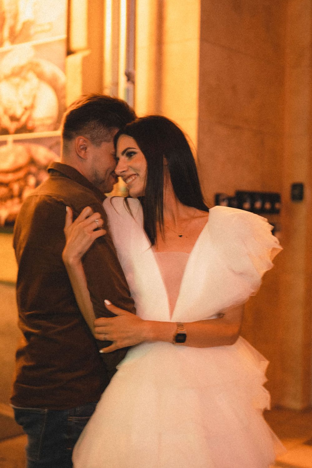 Intimate moment captured in warm golden lighting against urban backdrop.