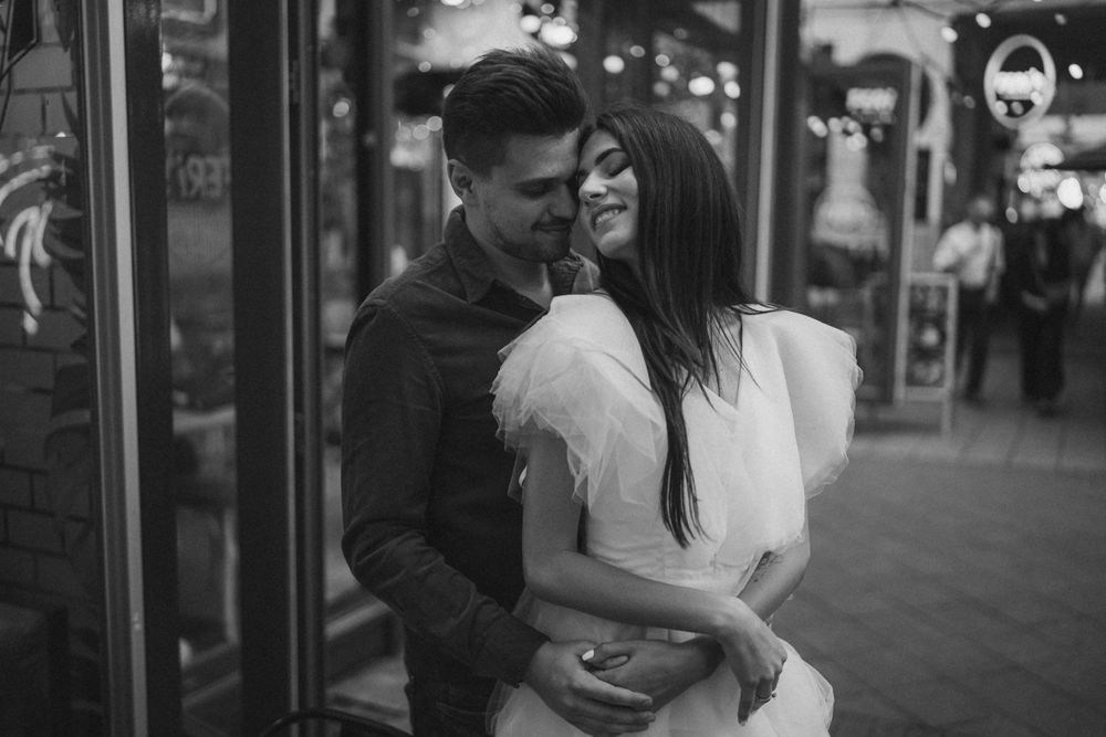 A black and white capture of a romantic moment outside an urban storefront.