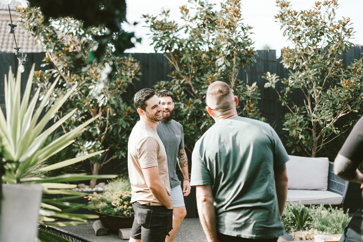 People gathered in outdoor garden space with flowering plants and modern landscaping.